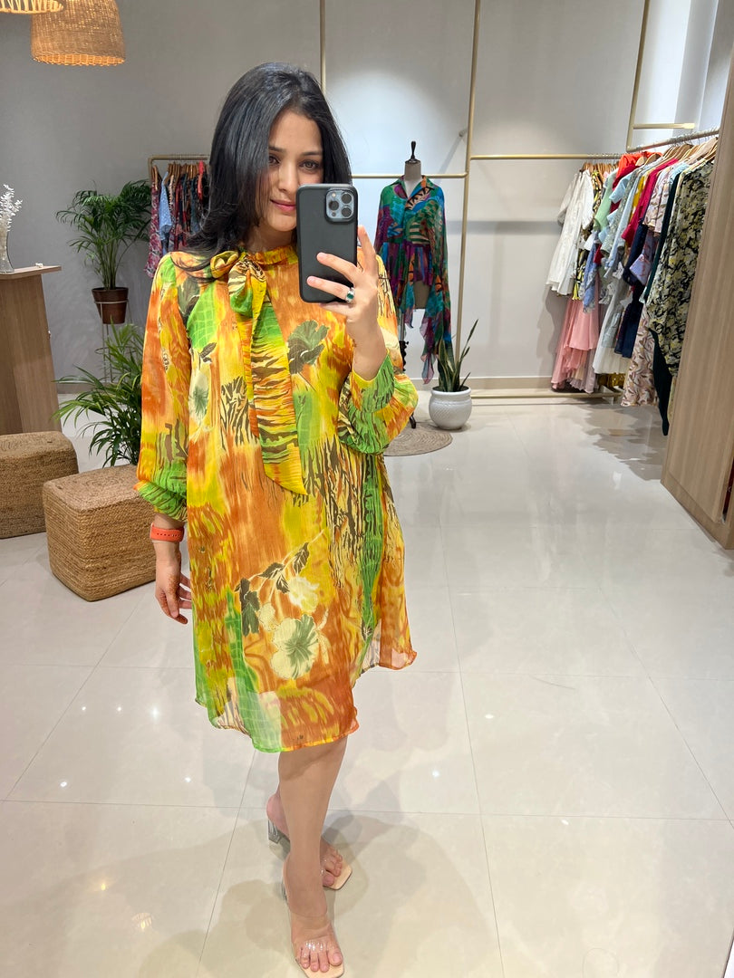 Woman taking a mirror selfie wearing a colorful dress in a room with a white floor.